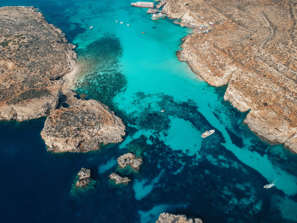 441191819_811753433919123_1773662194690867491_n Stunning drone shot of Comino, Malta showcasing crystal-clear turquoise waters and rugged coastline, perfect for a Comino day trip adventure.