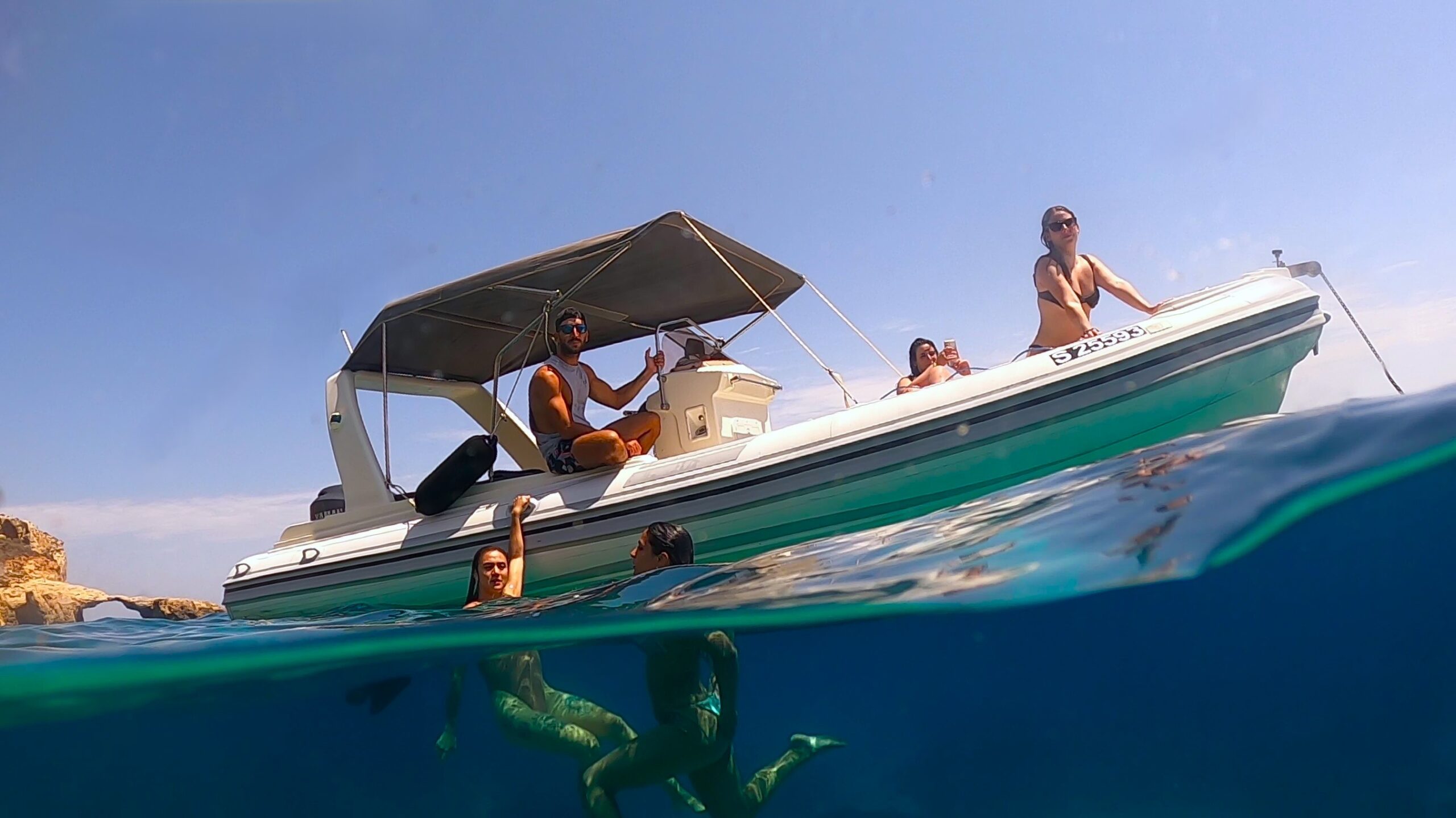 GOZOblu private boat with passengers enjoying a swim in the crystal-clear waters of the Blue Lagoon Malta Boat Trip experience.