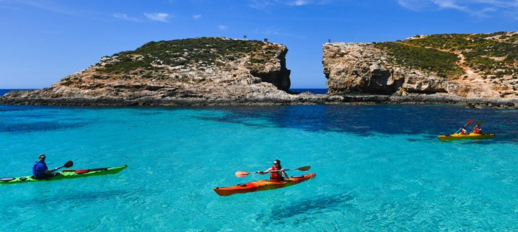 Kayakers enjoying the crystal-clear waters of Blue Lagoon Malta, surrounded by stunning natural scenery and vibrant blue waters.