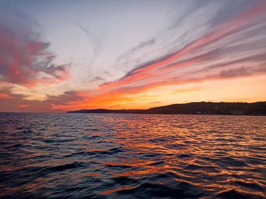 Golden sunset over Comino Beach, Malta, with the sun casting a warm glow on the calm turquoise waters