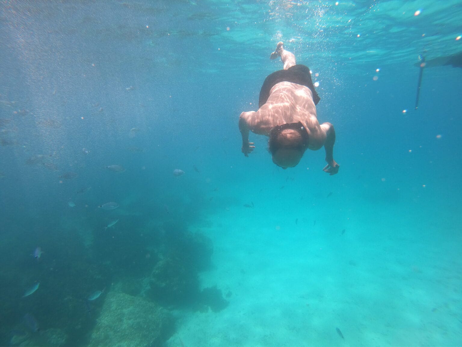 Tourist snorkelling in the clear turquoise waters of Xlendi Bay, one of the best places to snorkel in Malta. Discover vibrant marine life and stunning underwater landscapes in this popular Gozo destination, perfect for snorkelling enthusiasts and nature lovers alike.