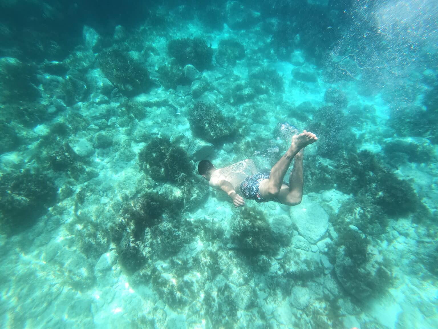 Tourist snorkelling in the clear blue waters of Għar Lapsi, a hidden coastal gem known as one of the best places to snorkel in Malta. Explore rocky reefs, marine life, and natural underwater beauty in this peaceful snorkelling spot.