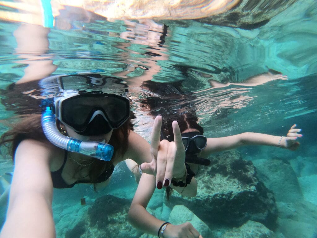 Tourist snorkelling in the clear turquoise waters of Imġiebaħ Bay, one of the best places to snorkel in Malta. This secluded bay offers vibrant marine life and a peaceful atmosphere, perfect for underwater exploration and nature lovers.