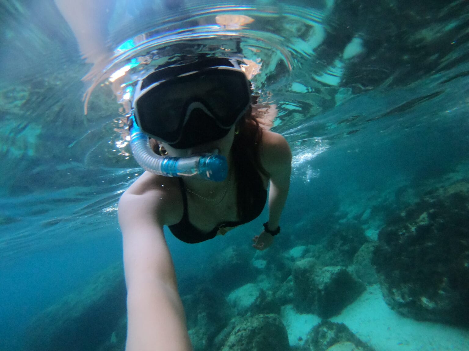 A tourist snorkelling in the crystal-clear waters of Tal-Fessej, one of the best places to snorkel in Malta. The vibrant marine life and pristine underwater landscapes make this location a must-visit for snorkelling enthusiasts. Discover the hidden treasures of Malta's coastline with a private boat tour from GOZOblu Private Boat Tours for an unforgettable experience.