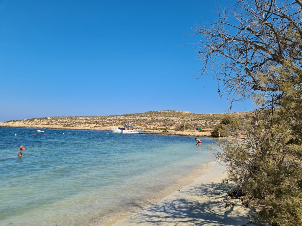 Scenic view of Santa Maria Bay, Malta, with clear turquoise waters and a tranquil sandy beach.