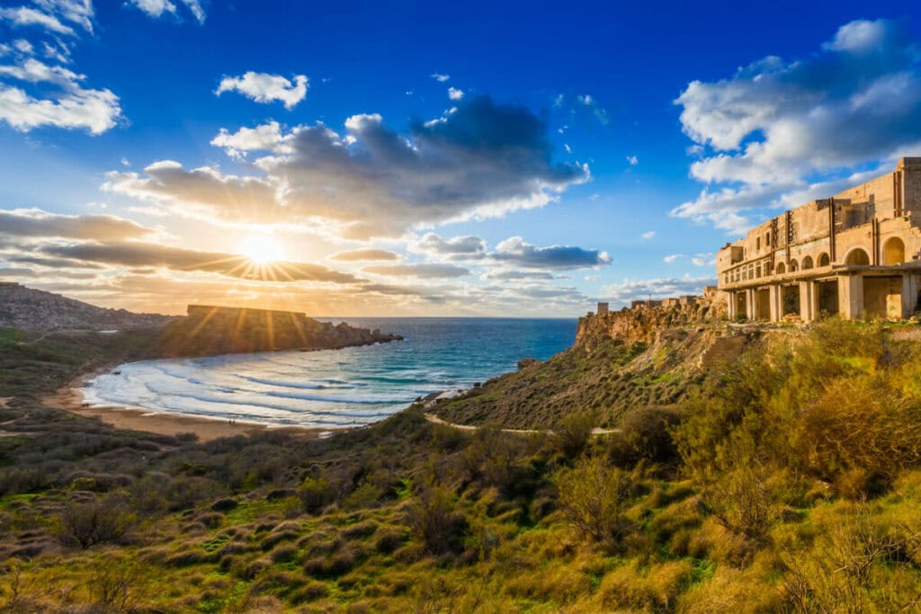 Stunning view of Għajn Tuffieħa Bay, Malta, with its golden-red sands, clear blue waters, and surrounding lush green cliffs