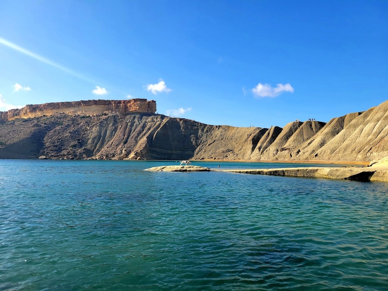 Local cliff jumping spot at Għajn Tuffieħa Bay in Malta, featuring clear blue waters and scenic limestone cliffs.