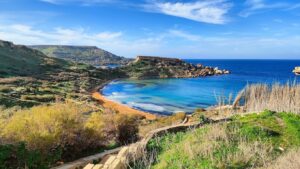 Scenic view of Għajn Tuffieħa Bay in Malta with golden sandy beach, crystal-clear waters, and dramatic cliffs.