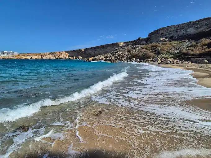 3-1 A close-up shot of the crystal-clear turquoise water at the shoreline, with gentle waves lapping the golden sand.