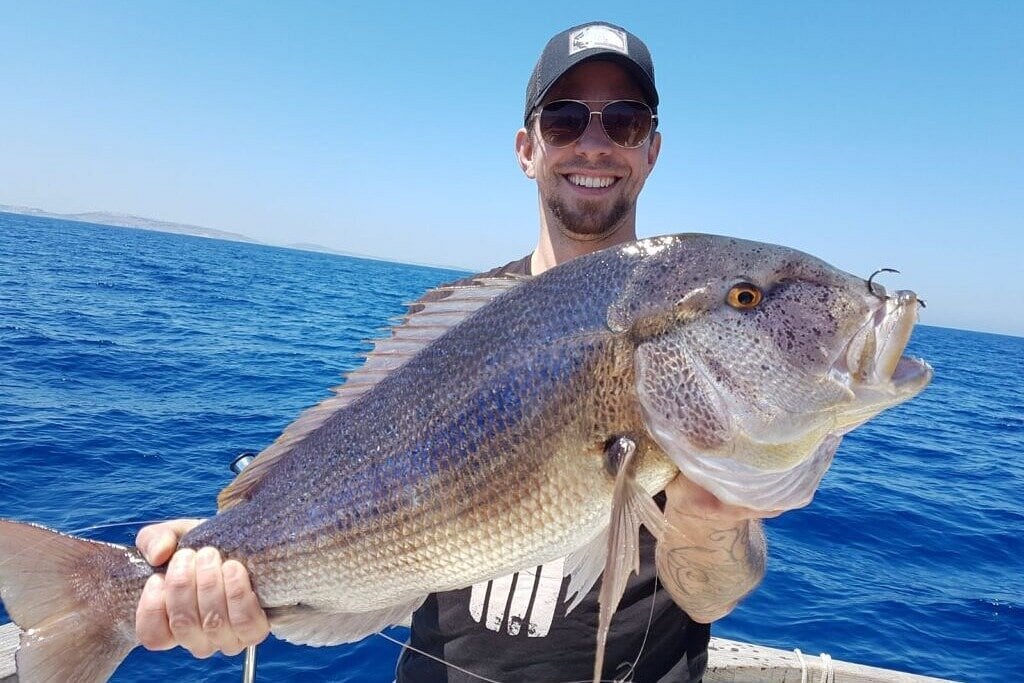 Happy angler proudly holding a big catch during exciting fishing trips in Malta along the Mediterranean coast