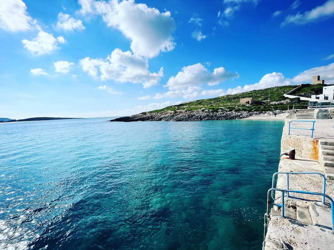 Scenic view of Bamberin Beach with clear blue waters and rocky shoreline, showcasing one of the best beaches in Malta and Gozo for swimming and relaxation.