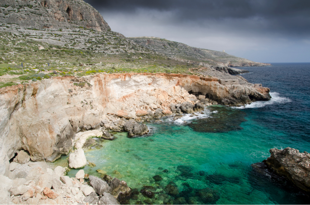 GOZOblu private boat tour at Għar Lapsi, Malta, showing crystal-clear waters and a hidden snorkelling spot along the rocky coastline.