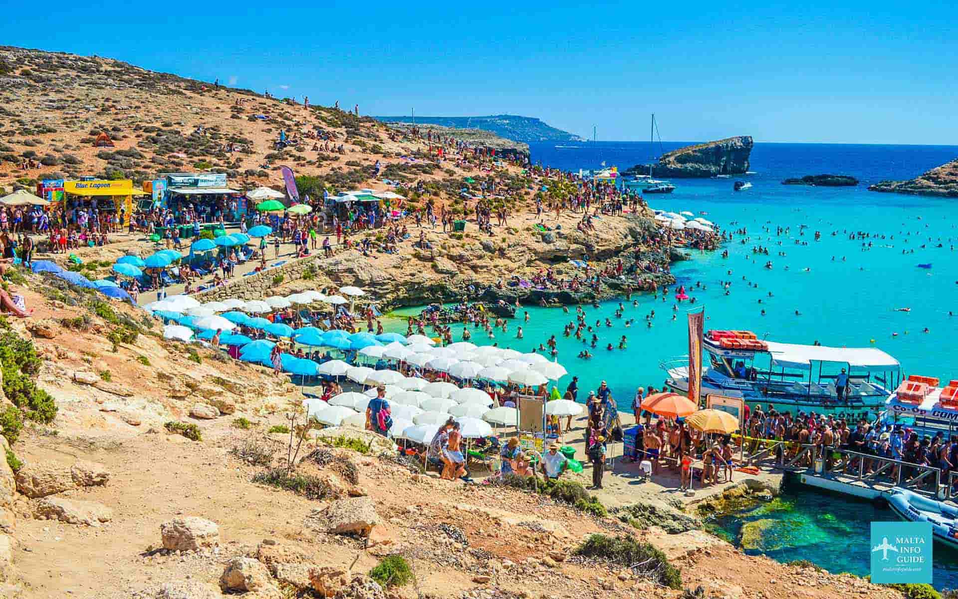 A packed Blue Lagoon in Malta with crystal-clear turquoise water and anchored boats filled with tourists enjoying the popular stop on many cruises from Malta.