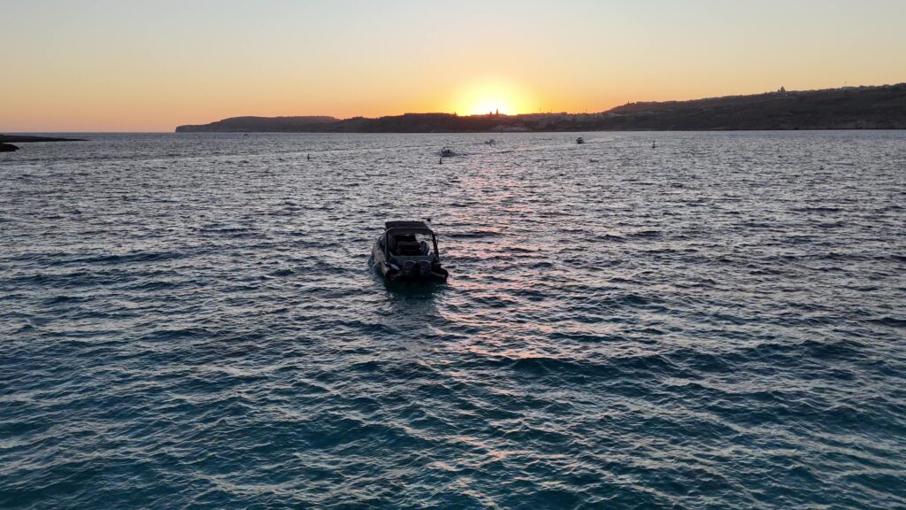 Friends enjoying a private boat tour in Malta, cruising across crystal-clear waters and taking in the beautiful Mediterranean coastline.