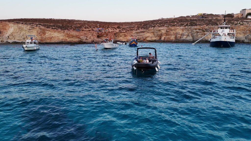 Tourists comparing self-drive boats with guided Malta boat tours on crystal-clear Mediterranean waters