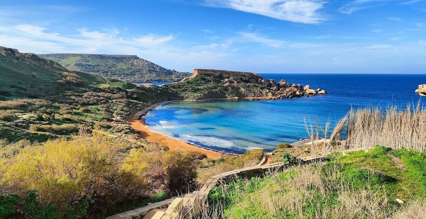 Għajn Tuffieħa Bay Scenic view of Għajn Tuffieħa Bay in Malta with golden sandy beach, crystal-clear waters, and dramatic cliffs.
