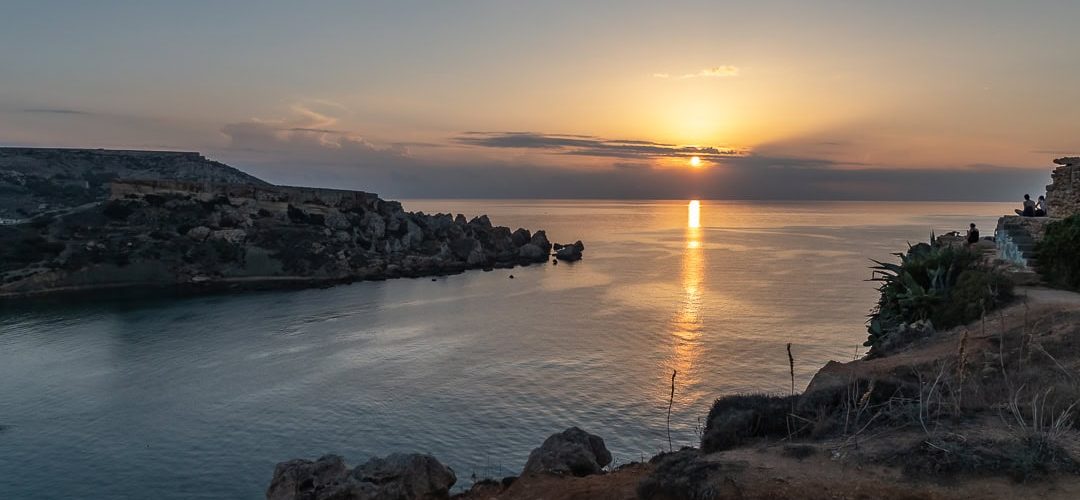 Ghajn Tuffieha Bay Sunset Sunset over Għajn Tuffieħa Bay in Malta with golden skies, rugged cliffs, and calm Mediterranean waters