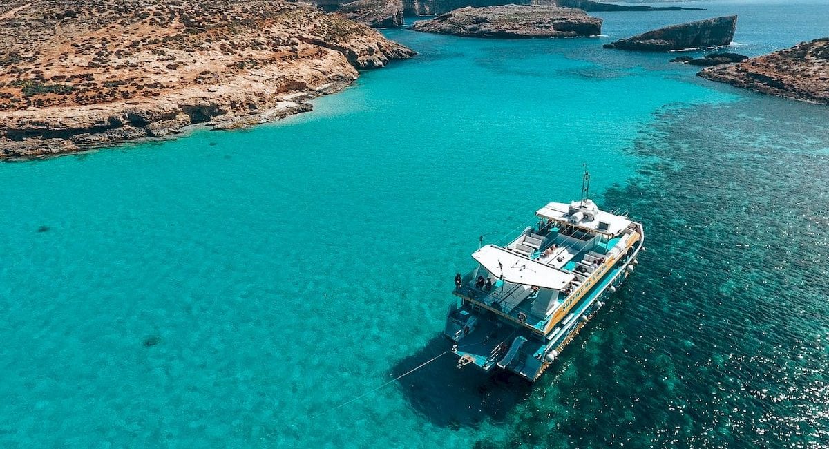 Private boat tour of Comino, Malta, with crystal-clear waters and scenic coastal views, showcasing a group aboard a boat exploring the island’s beauty.