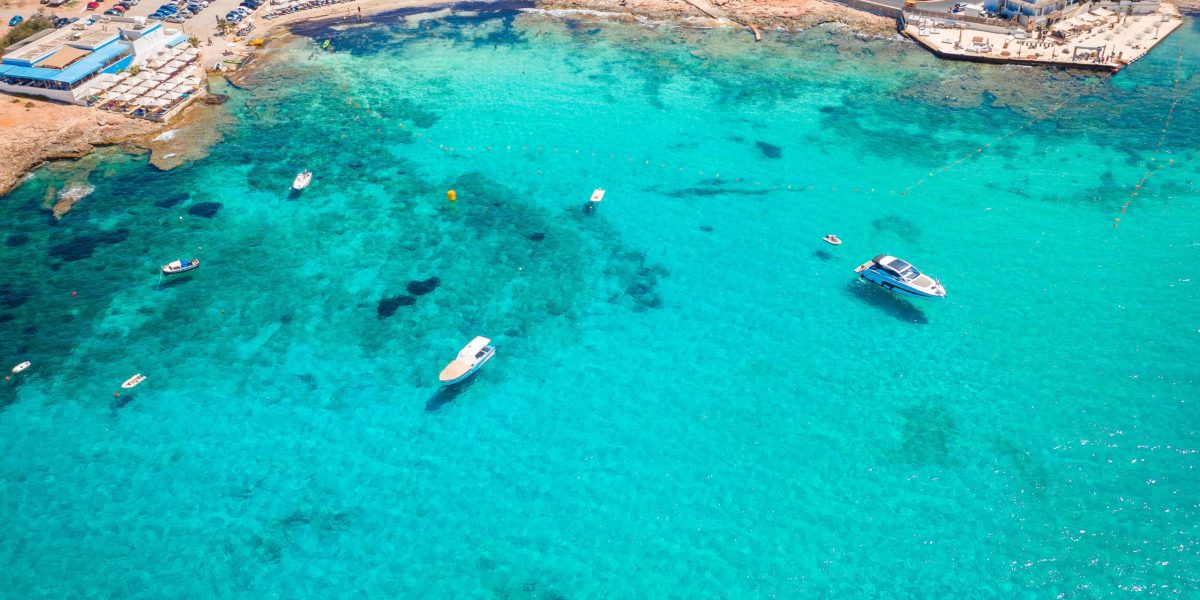 Aerial,View,Of,Armier,Bay Scenic view of the crystal-clear turquoise waters and sandy shoreline at Little Armier Bay Malta