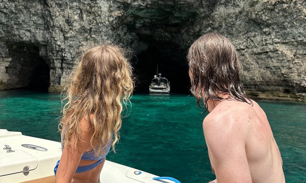 Couple enjoying a private boat tour on calm waters, surrounded by scenic views and clear blue skies.