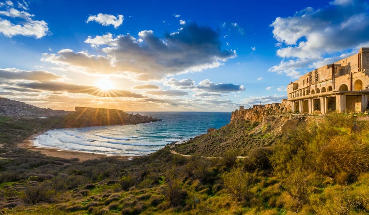 Stunning view of Għajn Tuffieħa Bay, Malta, with its golden-red sands, clear blue waters, and surrounding lush green cliffs