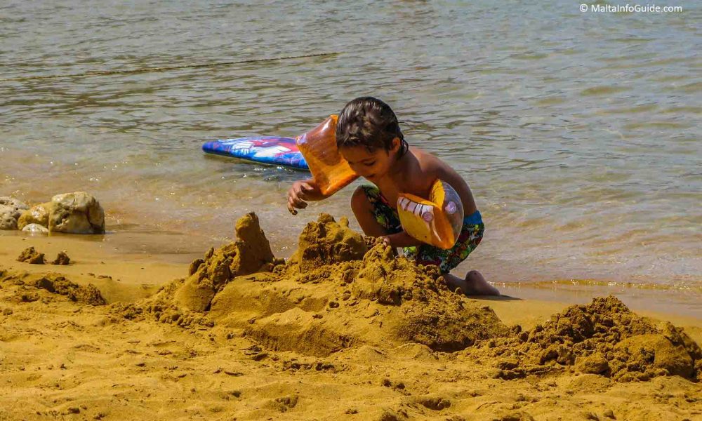 ramla-bay-gozo-best-beaches Child building a sandcastle on the golden-red sands of Ramla Bay, Gozo